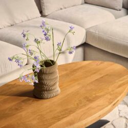 Elegante houten salontafel met natuurlijke afwerking geschikt voor moderne woonkamers, gecombineerd met een stijlvolle vaas en bloemen voor een gezellige sfeer.