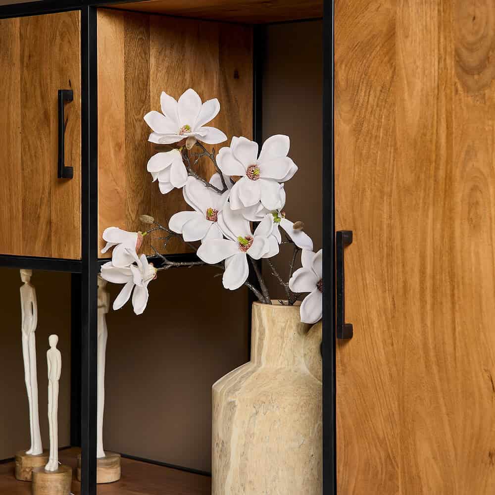 Echte magnoliabloem in een houten en metalen meubelstuk, decoratief interieuraccessoire voor een moderne woonstijl.