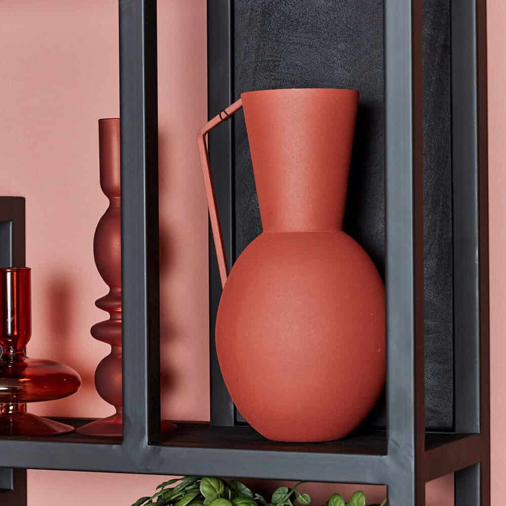 Vaas van keramiek op zwart metalen boekenrek, stijlvolle interieurdecoratie met aardetinten en minimalistisch design.