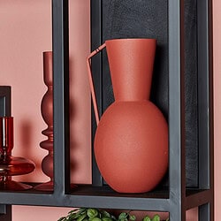 Vaas van keramiek op zwart metalen boekenrek, stijlvolle interieurdecoratie met aardetinten en minimalistisch design.