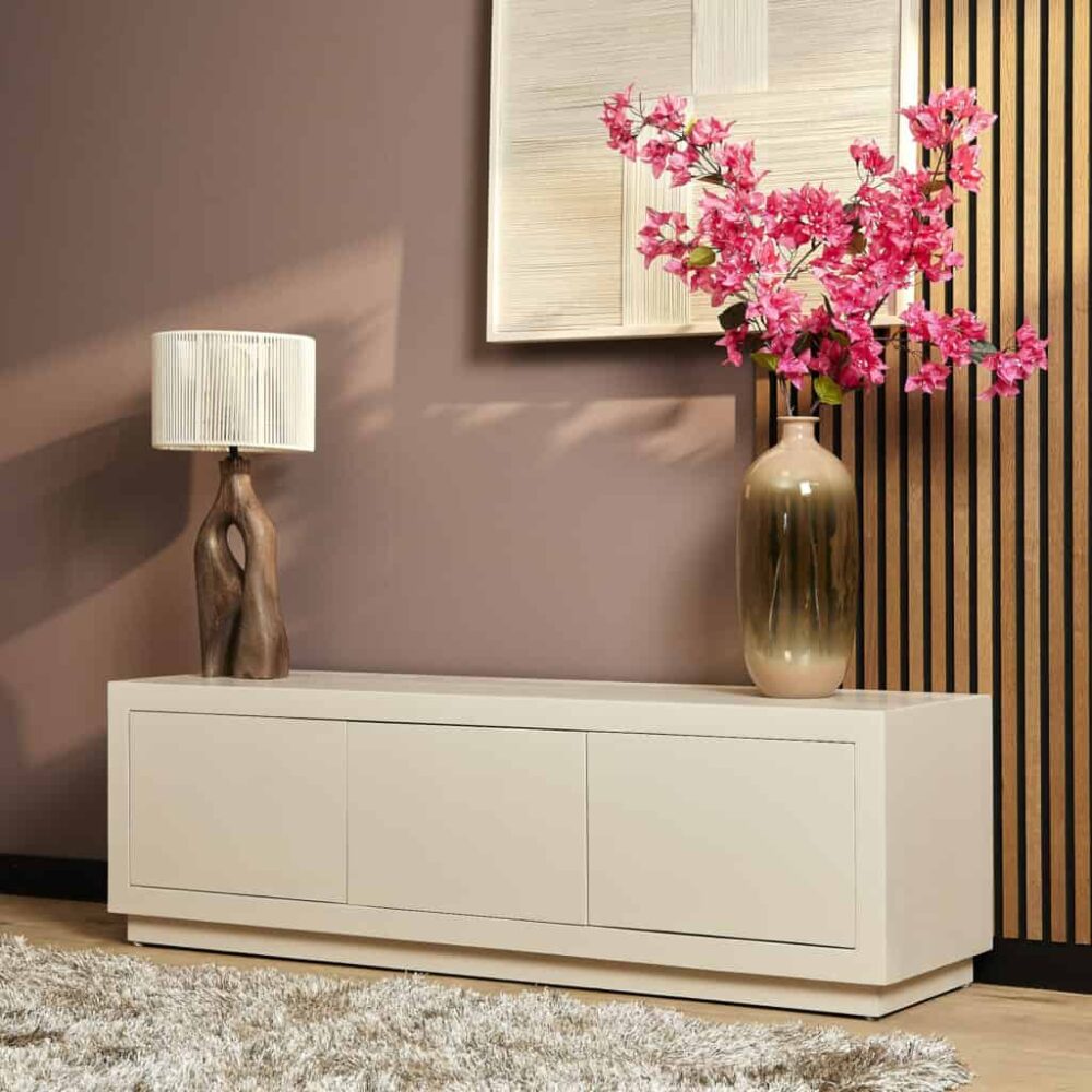 Strak witte houten tv-meubel met opbergruimte en decoratieve accessoires zoals een houten lamp en een grote vaas met roze bloemen, ideaal voor modern interieurdesign.