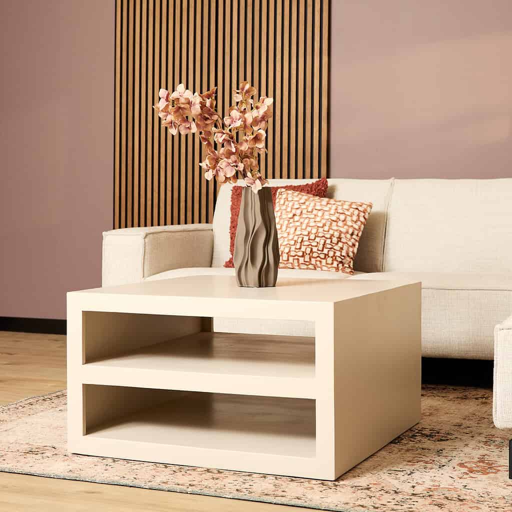 Gebroken witte bijzettafel met open vakken, perfect voor stijlvolle woonaccessoires, en bos bloemen op een modern bankstel, ideaal voor een warm en elegant interieur.