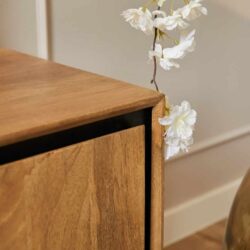 Elegante houten meubel met natuurlijke afwerking en zwart detail, gecombineerd met witte kunstbloemen voor een stijlvolle en warme sfeer.
