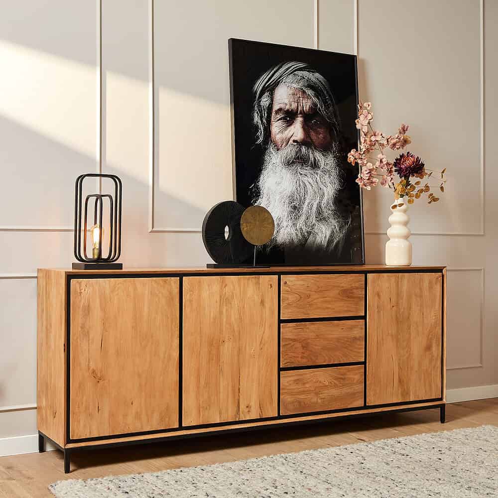 Robuuste houten sideboard met zwart metalen frame, perfect voor een moderne of Scandinavische woonkamer, voorzien van stijlvolle decoraties en een opvallend portret als eyecatcher.