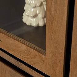 Houten meubel met glazen deur en decoratief sculptuur, vakmanschap en natuurlijke houtafwerking.