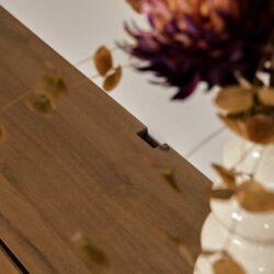 Modern houten tafel met zichtbaar houtstructuur en sierlijke bloemdecoratie, perfect voor een warme, natuurlijke sfeer in huis of kantoor.