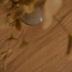 Natuurlijke houten tafel met een glazen vaas en decoratieve takken voor een warme, gezellige sfeer. Perfect voor stijlvolle woonkamer of eetkamer interieurs.