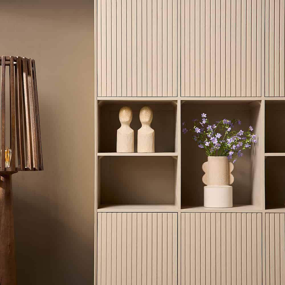 Strak houten opbergkast met verticale groeven en decoratieve accessoires, perfect voor een Scandinavische woonstijl.