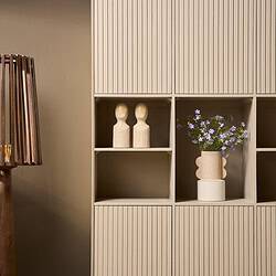 Strak houten opbergkast met verticale groeven en decoratieve accessoires, perfect voor een Scandinavische woonstijl.
