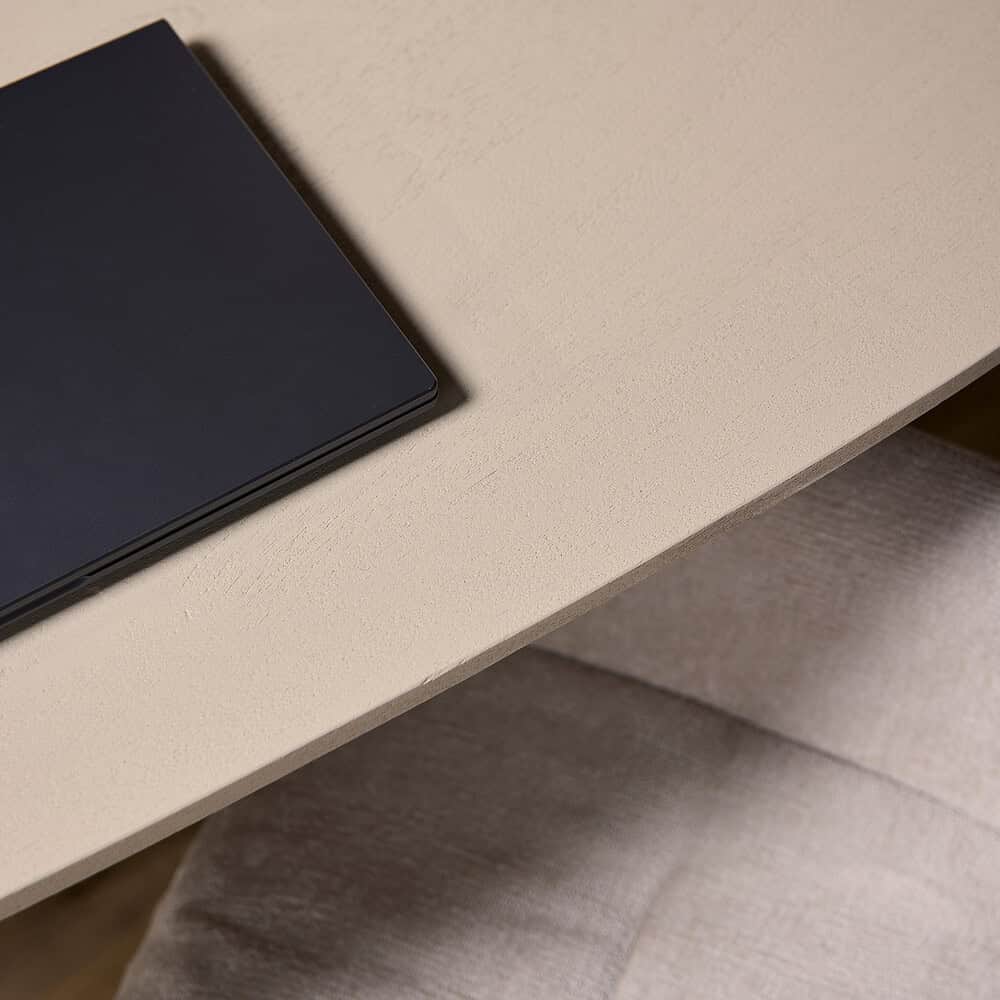 Strakke beige tafel met een zwart notitieboekje op het oppervlak, ontworpen door Mokana Meubelen voor een modern interieur.