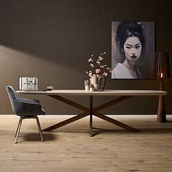 Elegante eettafel met moderne design van Mokana Meubelen, gecombineerd met een stijlvolle fauteuil, kunstglaswerk en een opvallende portret schilderij voor een verfijnde interieurstijl.