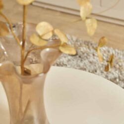 Droogbloemen in een glazen vaas op een witte tafel, houtenvloer en warme interieurstijl. Mooi decoratief item voor woonkamer of eetkamer met natuurlijke uitstraling.