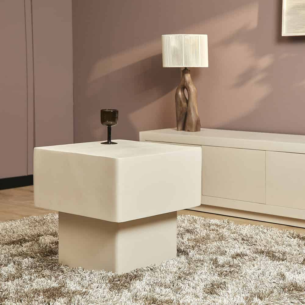 Strak wit bijzettafel in modern woonkamer met blush muur en houten lamp, stijlvol en functioneel.