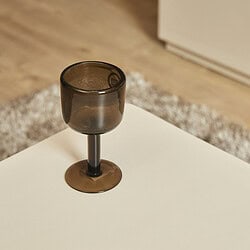 Gezellige donkere wijn- of cocktailglas op een witte tafel, in een interieur met zachte, warme uitstraling en houten vloer, perfect voor moderne en stijlvolle woonkamer of eetkamer.