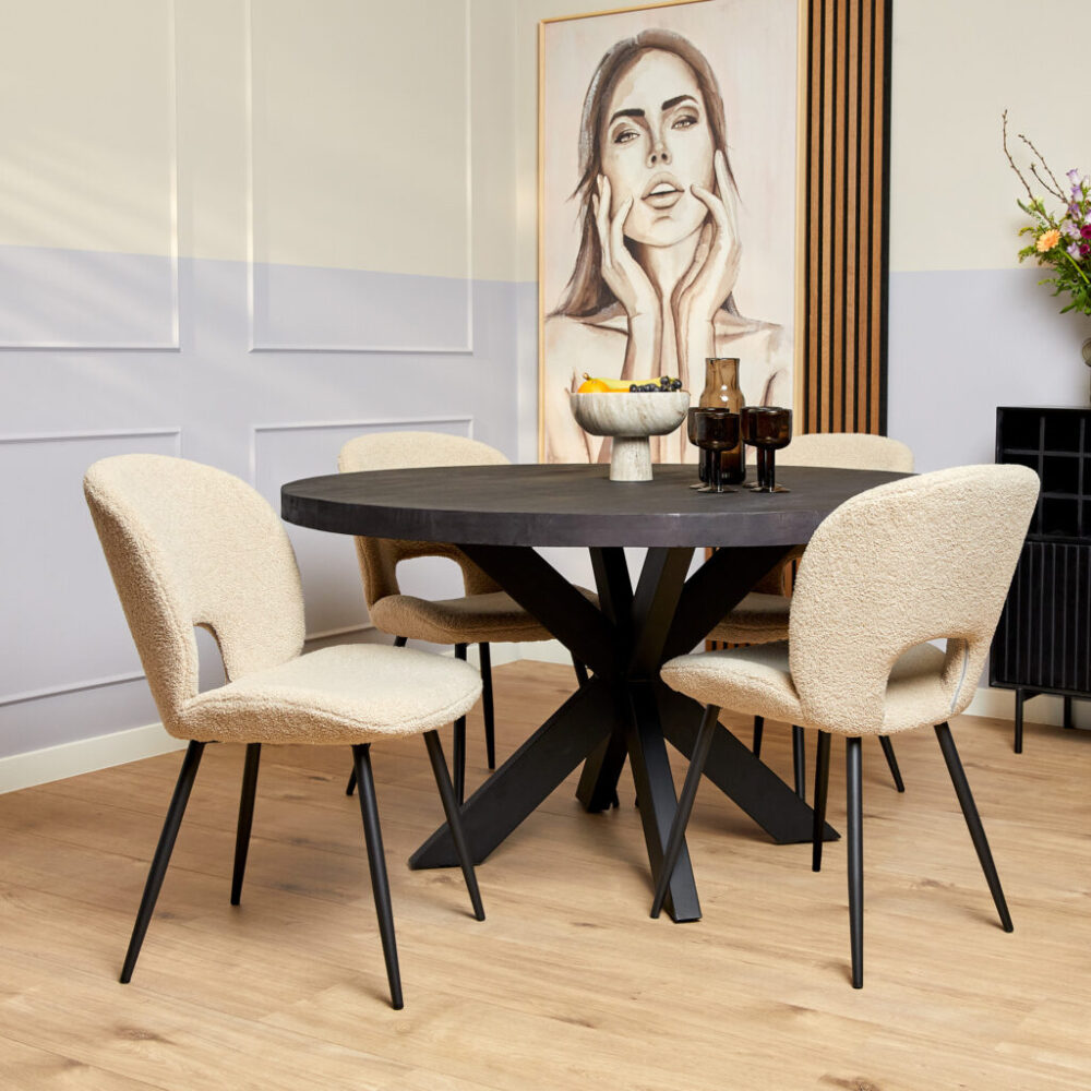 Stijlvolle eettafel met zwarte onderstellen en beige geweven stoelen, modern interieur met kunstwerk en decoratieve accessoires.
