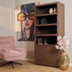 Vintage houten boekenkast met opbergvakken en decoratieve accessoires, gecombineerd met een chic roze fauteuil en een kunstzinnig portret voor een stijlvolle woonkamer.