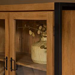 Houten vitrinekast met zwart metalen accenten en een glazen deur, perfect voor het tonen van decoratieve objecten en meubelstukken.