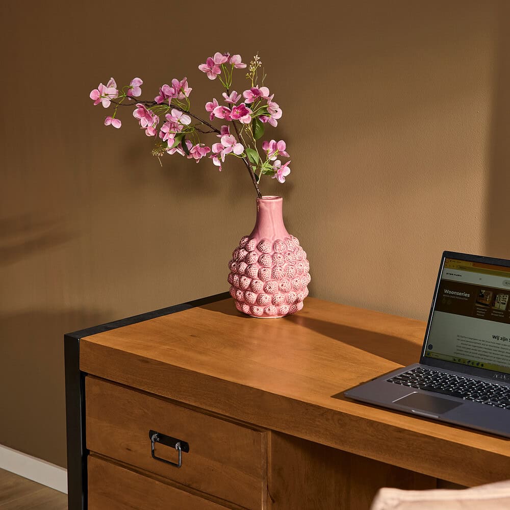 Roze keramische vaas met orchideeën op een houten bureau, modern interieur met natuurlijke materialen en stijlvolle woonaccessoires.