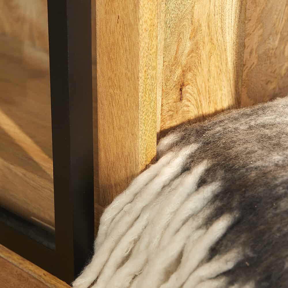 Hoogwaardig houten meubel met zwarte metalen accenten en een dikke schapenvacht onder de tafel voor een warme, landelijke uitstraling.