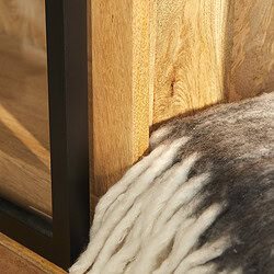 Hoogwaardig houten meubel met zwarte metalen accenten en een dikke schapenvacht onder de tafel voor een warme, landelijke uitstraling.