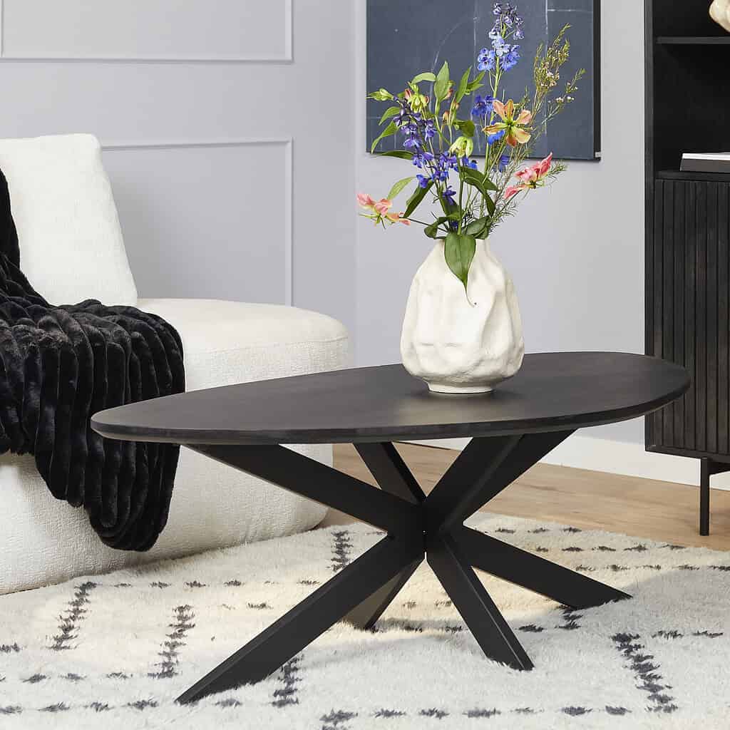 Elegante zwarte salontafel met unieke X-vormige poten, perfect voor modern interieur, gecombineerd met witte bank en decoratieve vazen.