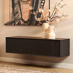Strakke zwarte wandmeubel met geribbelde deuren, gecombineerd met ceramicistische vazen en roze bloemen, in een modern interieur met kunstwerk en zachte verlichting.