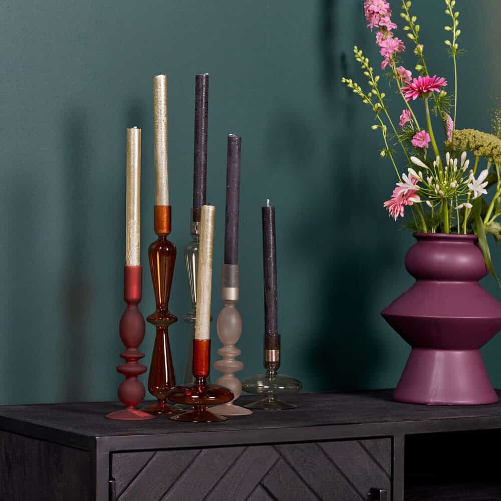 Geschilderd beeld van kaarsen en bloemen in een tuin, elegante houten kandelaren en een grote paarse vaas met kleurrijke bloemen, stijlvolle decoratie voor woonkamer of tuin.