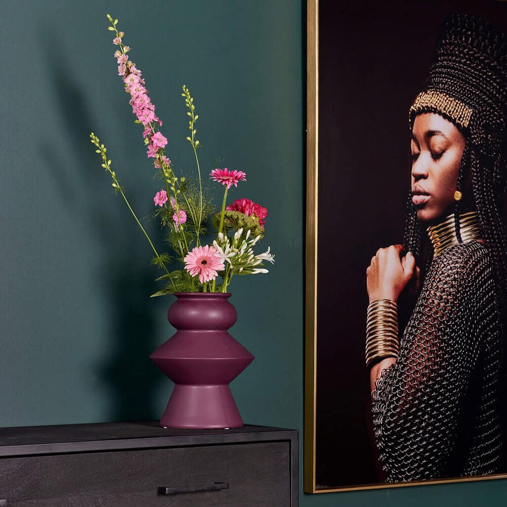 Vase met kleurrijke bloemen op een zwart meubelstuk in een modern interieur.