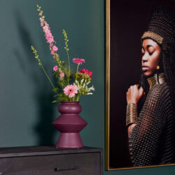 Vase met kleurrijke bloemen op een zwart meubelstuk in een modern interieur.