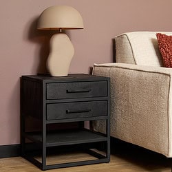 Modern bijzettafel met 2 lades en open onderste plank, zwart houten afwerking, naast een beige stoffen bank en sierkussen, perfecte woonaccessoire voor een eigentijds interieur.