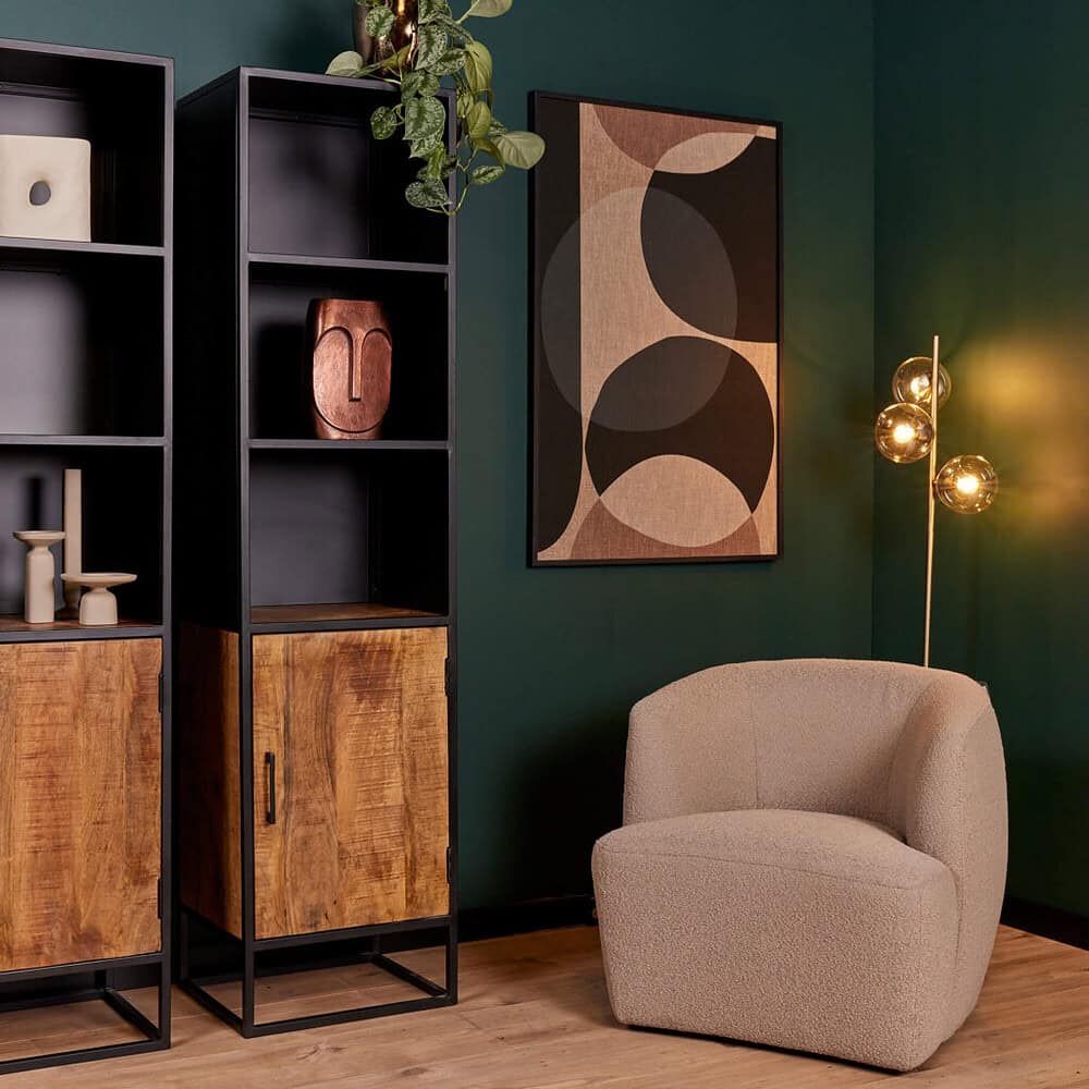 Moderne industriele boekenplank en een comfortabele armstoel in een stijlvolle woonkamer met wanddecor en sfeervolle vloerlamp.