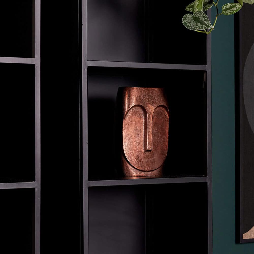 Minimalistische zwarte boekenkast met decoratieve aardetint beeldsieraad en groene planten, modern interieurdesign.