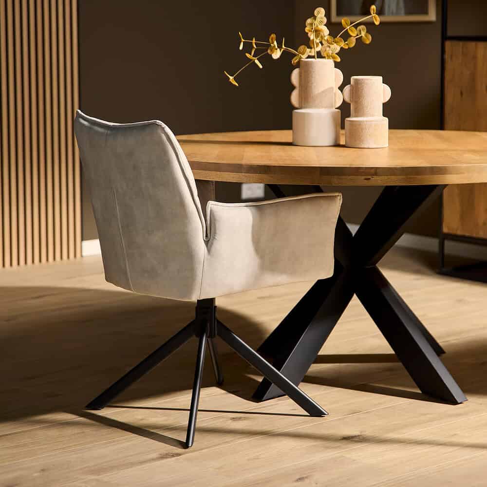 Elegante eetkamerstoel met beige fluwelen bekleding en zwarte metalen poot, gecombineerd met een massief houten eetkamertafel en stijlvolle decoratie voor een warm en modern interieur.