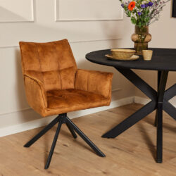 Leren stoelen met zwart metalen onderstel en een rond houten eettafel met decoratieve vaas en keramische kommen in een moderne eetkamer.