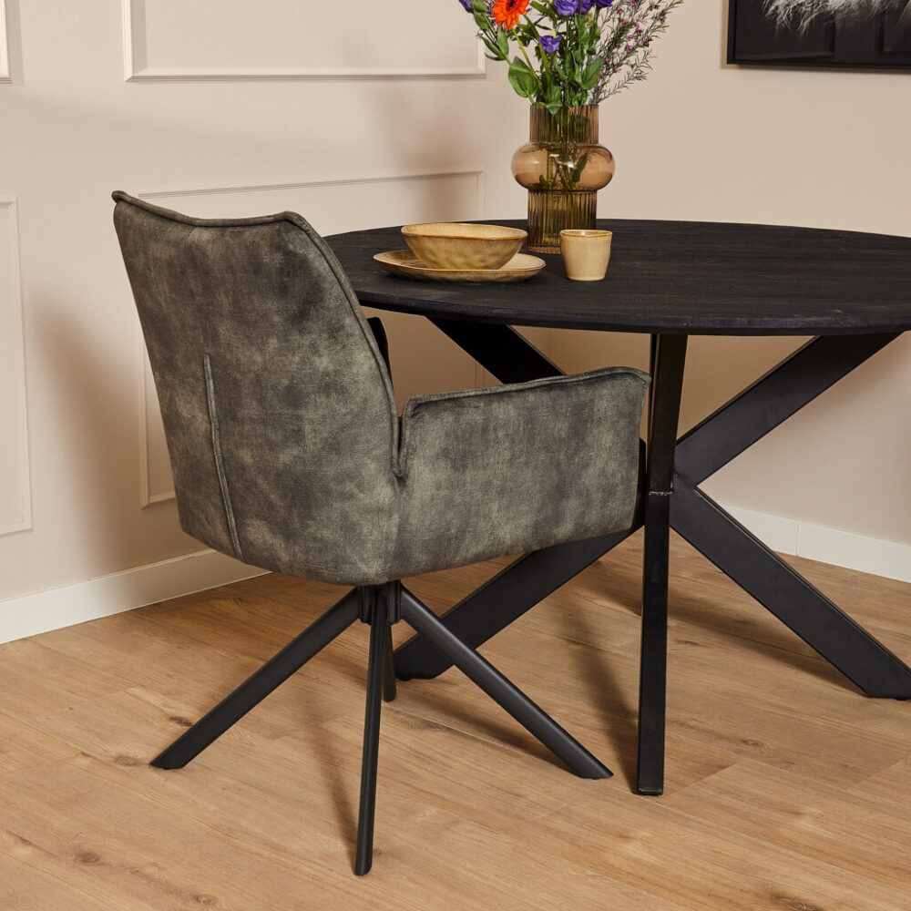 Modern eettafel met zwart metalen onderstel en bijpassende comfortabele vergadestoel in een sfeervolle woonruimte.