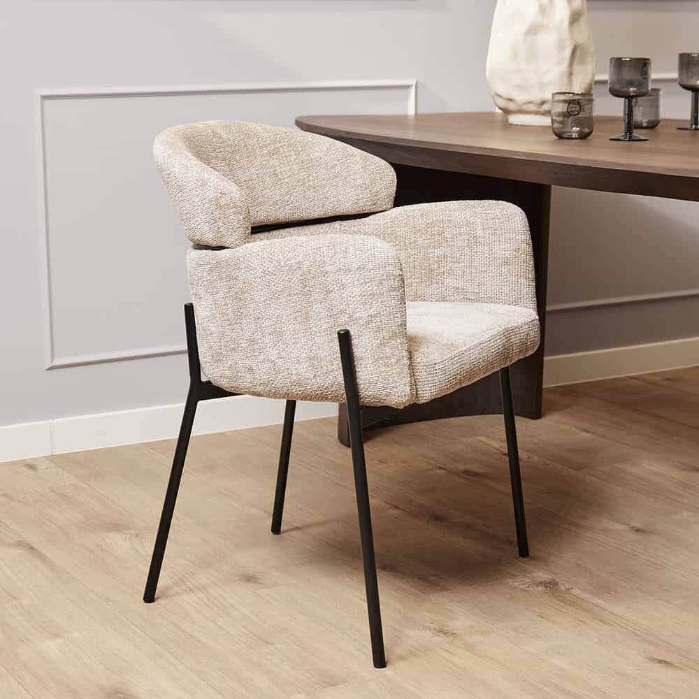 Elegant beige stoffen eetkamerstoel met zwarte metalen poten van Mokana Meubelen, ideaal voor moderne eetkamers en stijlvolle interieurdesigns.