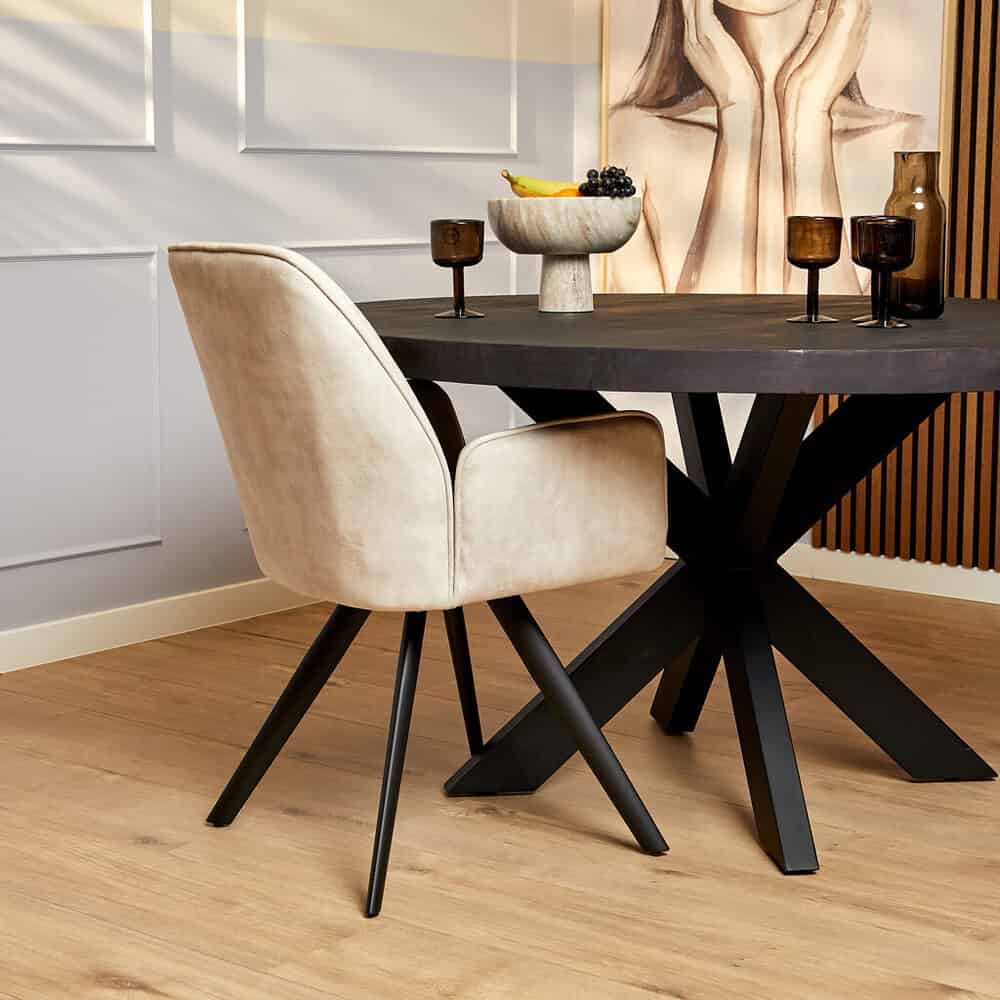 Elegante dining tafel met zwart metalen onderstel en beige velvet stoel, perfect voor modern interieur.