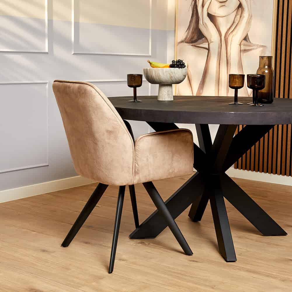 Moderne eetkamerstoel met beige suède bekleding en zwarte houten poten, passend bij houten eettafel, in stijlvolle interieursetting.