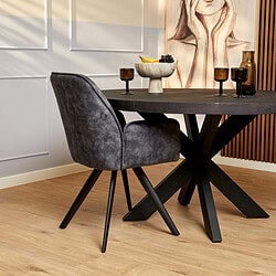 Elegant zwart houten eettafel met moderne vierkante onderstel, gecombineerd met een comfortabele grijze velvet eetkamerstoel in een stijlvol interieur.
