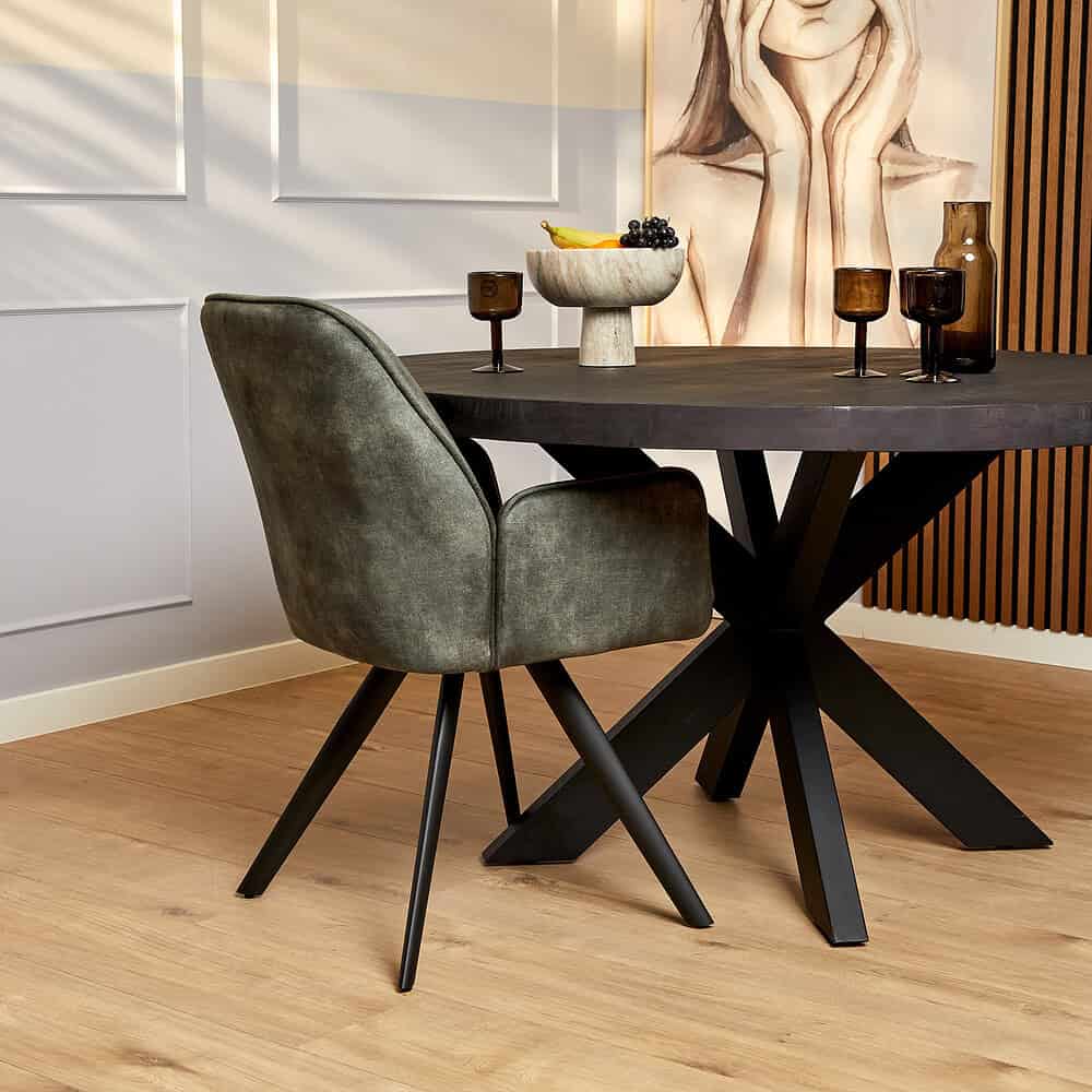 Elegante groene velvet eetkamerstoel bij zwart eettafel met sculptuurvorm, moderne en luxe meubelstukken voor een stijlvolle woonruimte.