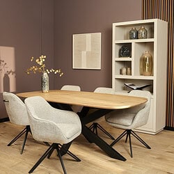 Modern eettafel met licht houten blad en zwarte X-vormige poot, omringd door comfortabele beige stoelen, met decoratieve vazen en een zachte warme sfeer.