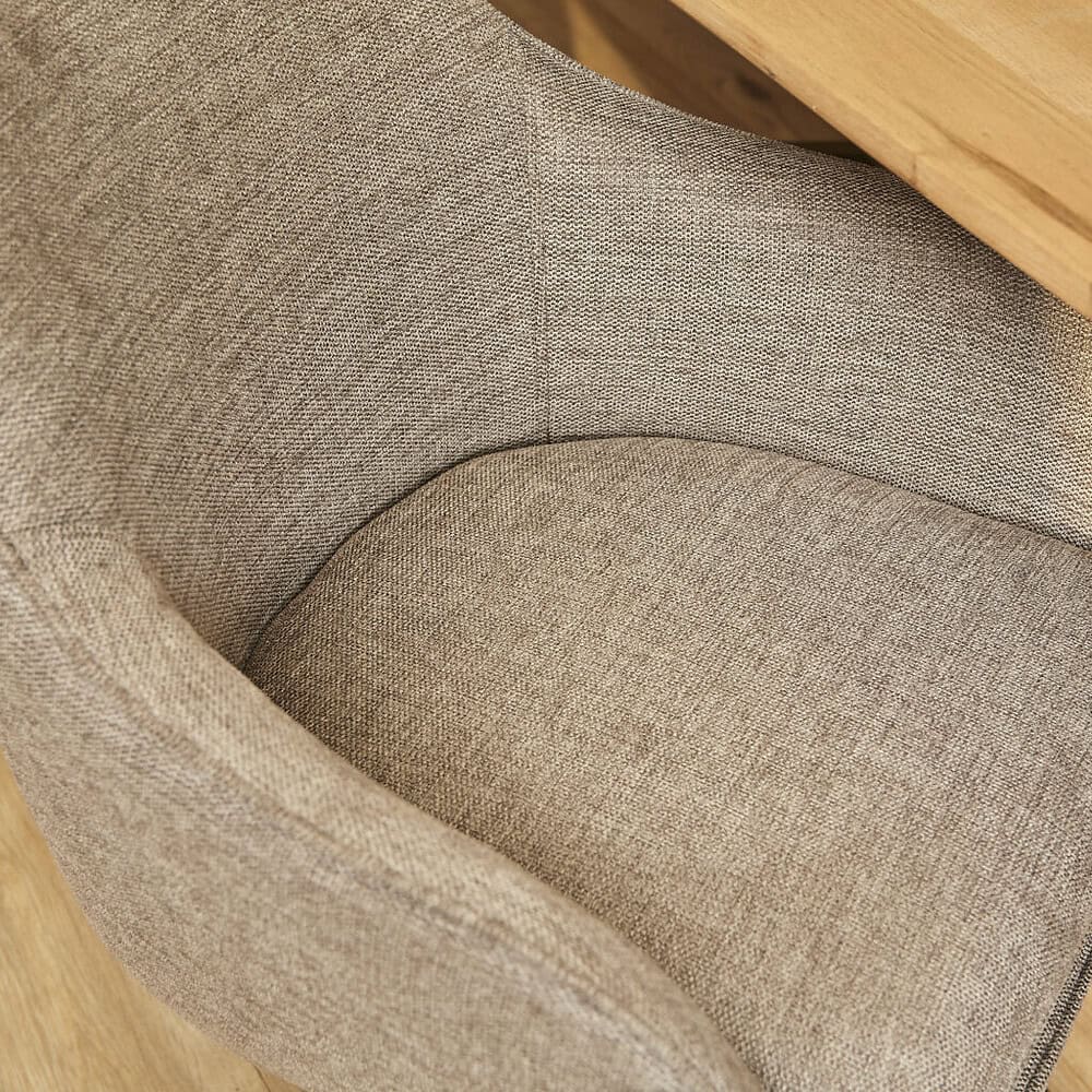 Rieten fauteuil met beige stoffen bekleding en houten armleuningen, perfect voor een gezellige en stijlvolle zithoek.