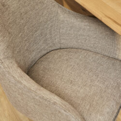 Rieten fauteuil met beige stoffen bekleding en houten armleuningen, perfect voor een gezellige en stijlvolle zithoek.