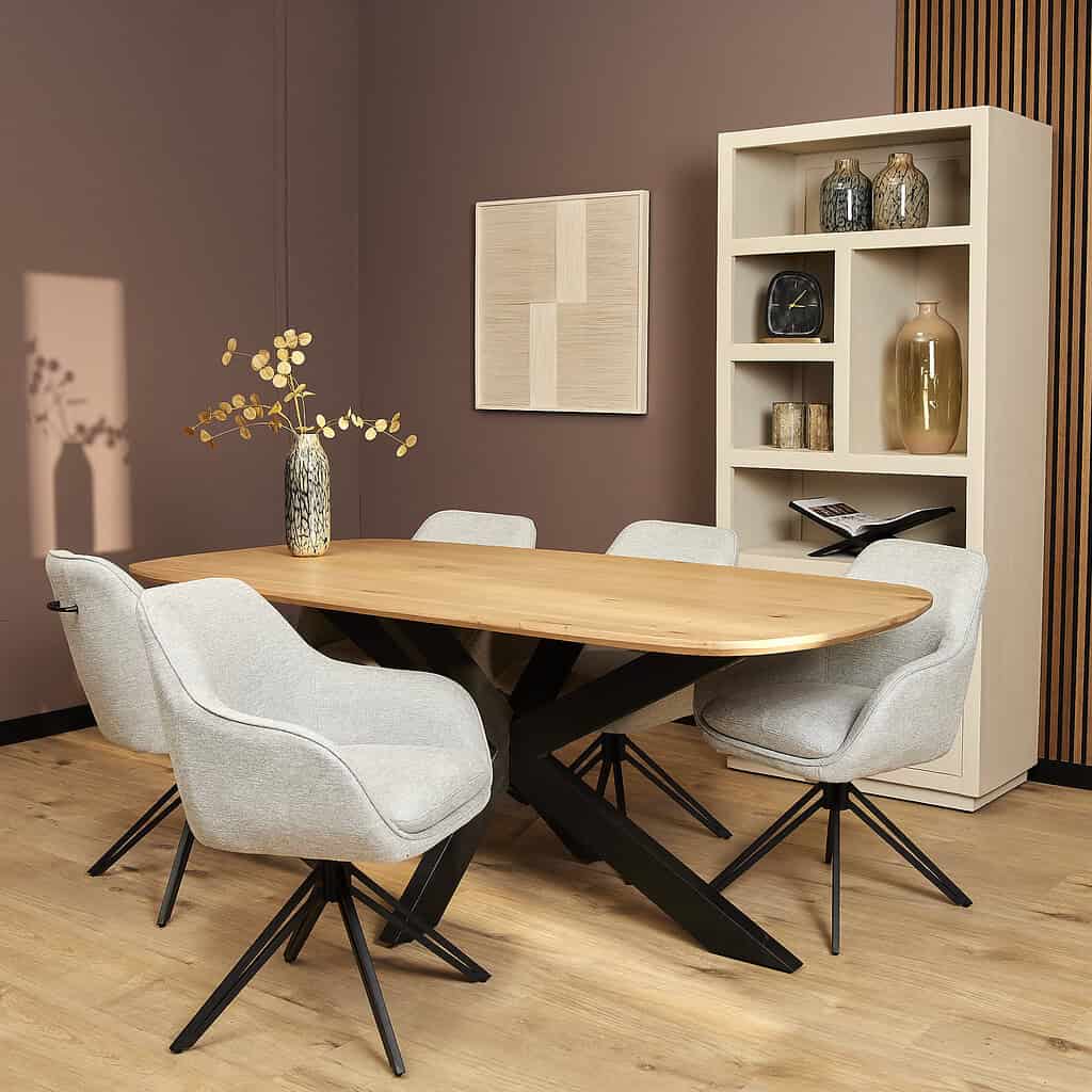 Elegant eettafel met houten blad en zwarte industriële onderstellen, omringd door comfortabele gestoffeerde eetkamerstoelen, in een modern interieur met decoratieve accessoires.