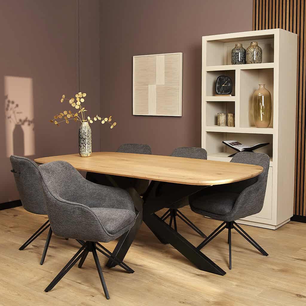 Elegante houten eettafel met zwart metalen onderstel, omringd door comfortabele grijze stoffen stoelen, in een moderne woonruimte met warme aardetinten en stijlvolle decoratie.