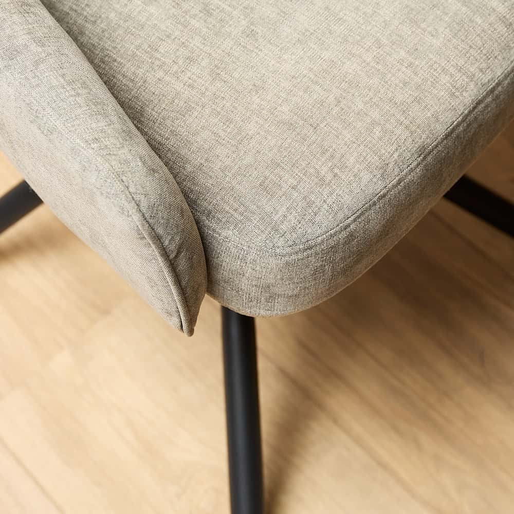 Elegant beige stoffen eetkamerstoel met zwarte metalen poten, comfortabel en stijlvol voor een moderne interieur.