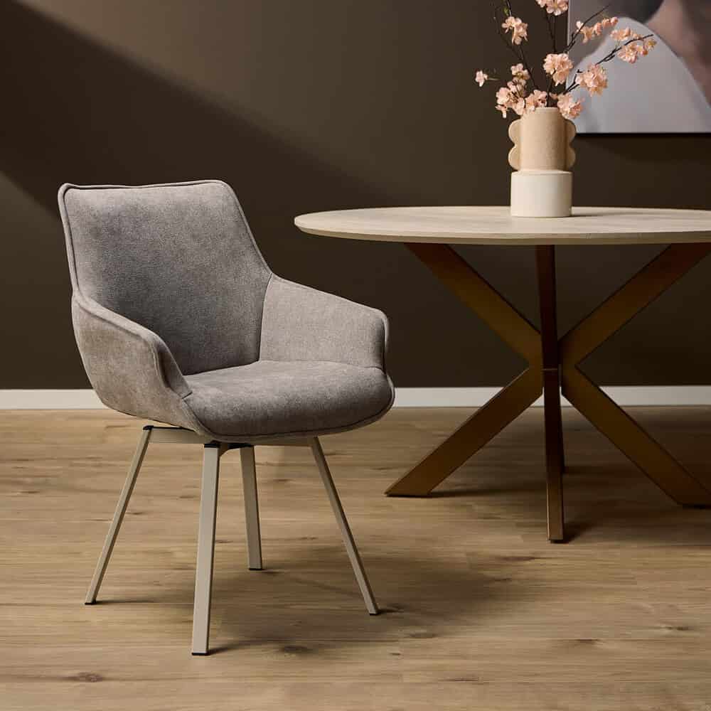 Zachte grijze eetkamerstoel met modern design op houten vloer met ronde eettafel en vaas met bloemen, ideaal voor stijlvolle interieur decoratie en comfort.