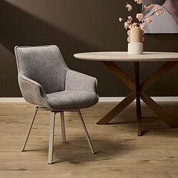 Zachte grijze eetkamerstoel met modern design op houten vloer met ronde eettafel en vaas met bloemen, ideaal voor stijlvolle interieur decoratie en comfort.