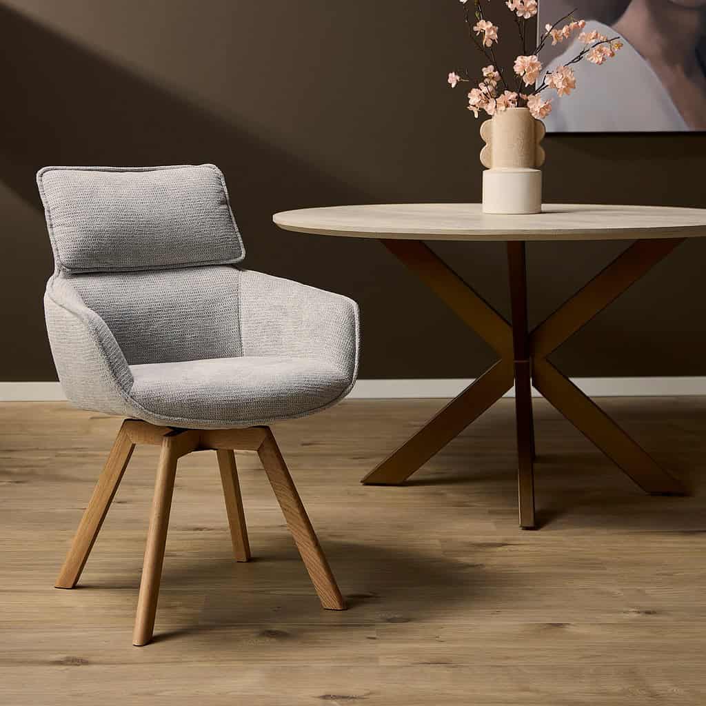 Elegante houten stoel met comfortabel lichtgrijs gestoffeerd zitvlak en rugleuning, gecombineerd met een luxe eettafel en decoratieve bloemenvase in een modern interieur.