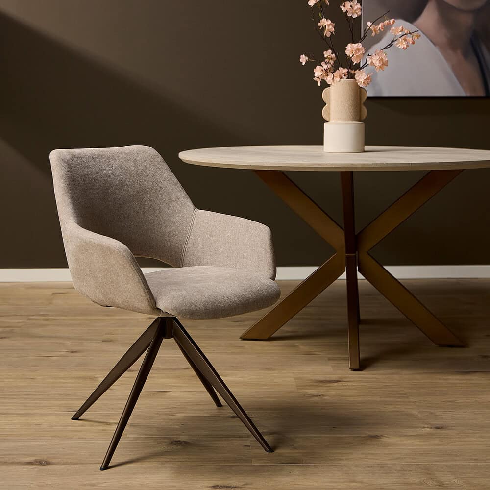 Eetkamerstoel van zacht beige stoffering met elegante draaivoet, gecombineerd met een modern eettafel met een houten blad en metalen pootconstructie, in een stijlvol wooninterieur.
